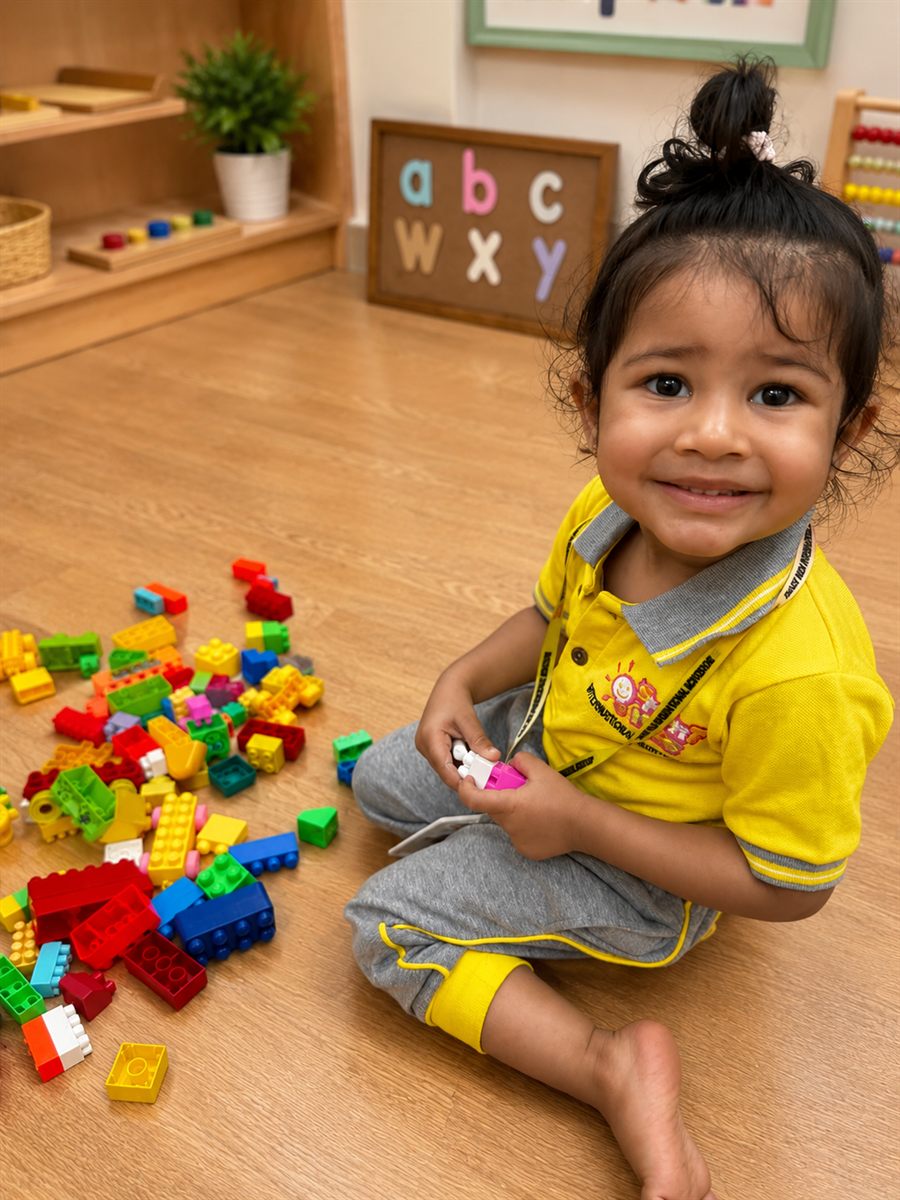 A toddler exploring colourful building blocks beside an alphabet board